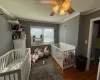 Bedroom with cooling unit, wood finished floors, a ceiling fan, a nursery area, and crown molding