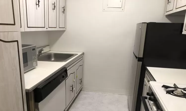 Kitchen with baseboards, stainless steel appliances, a sink, and light countertops