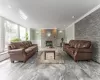 Living area featuring ornamental molding, wainscoting, a decorative wall, and a stone fireplace