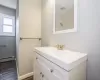 Bathroom with a baseboard heating unit, wood finish floors, visible vents, vanity, and baseboards