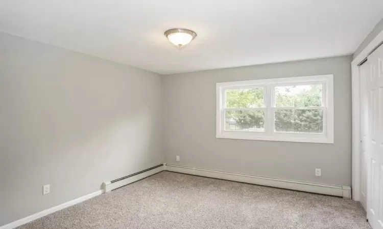 Unfurnished room with carpet and a baseboard heating unit