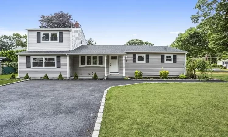 View of front of home featuring aphalt driveway, a front lawn, and a shingled roof