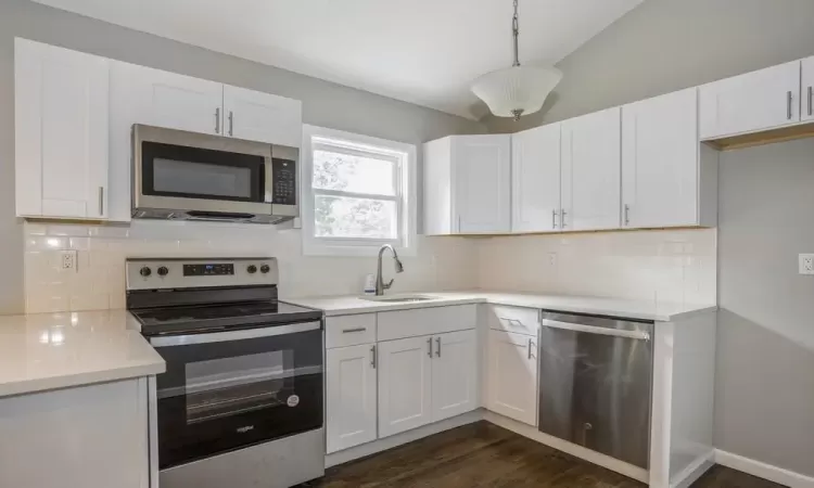 Kitchen featuring stainless steel appliances, a sink, and white cabinets