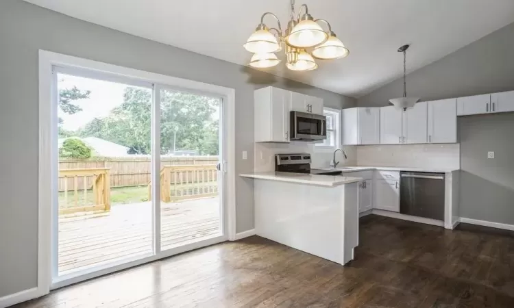 Kitchen featuring appliances with stainless steel finishes, a wealth of natural light, a sink, and dark wood-style floors