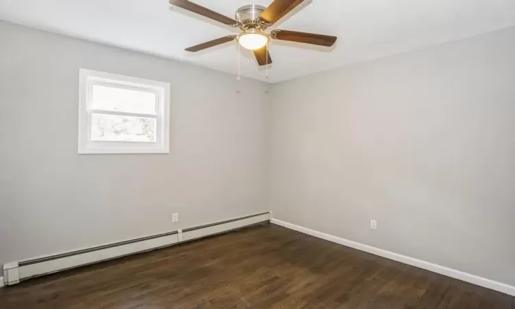 Unfurnished room with a ceiling fan, a baseboard radiator, baseboards, and wood finished floors