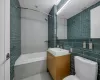 Bathroom with decorative backsplash, toilet, tiled shower / bath combo, vanity, and tile walls