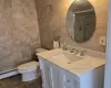 Bathroom featuring toilet, baseboard heating, tile walls, and vanity