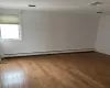 Unfurnished room with hardwood / wood-style floors, a baseboard radiator, and visible vents