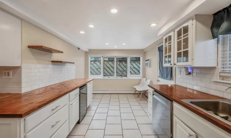 Kitchen featuring a baseboard heating unit, dishwasher, wood counters, and open shelves