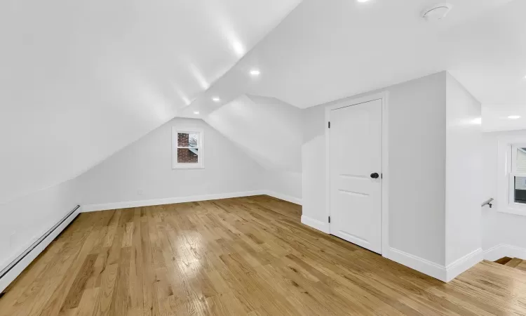 Bonus room featuring baseboards, lofted ceiling, hardwood / wood-style floors, baseboard heating, and recessed lighting