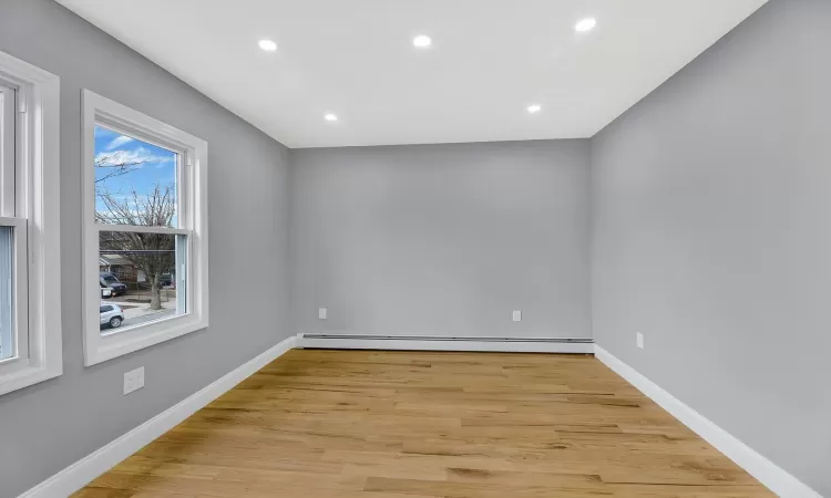 Spare room featuring a baseboard heating unit, light wood-style floors, and baseboards