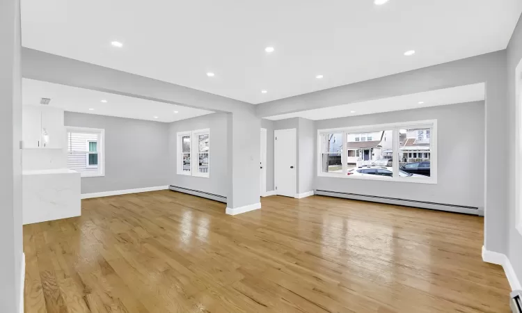 Unfurnished living room with light wood-style floors, a baseboard radiator, and baseboards