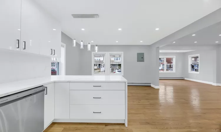 Kitchen with a peninsula, modern cabinets, a baseboard heating unit, and dishwasher