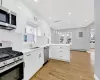 Kitchen featuring stainless steel appliances, a baseboard radiator, white cabinetry, a sink, and a peninsula