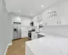 Kitchen with a sink, white cabinetry, appliances with stainless steel finishes, light wood-type flooring, and backsplash