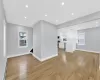 Unfurnished living room with light wood-style flooring, a baseboard heating unit, baseboards, and recessed lighting