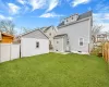 Rear view of house featuring a shingled roof, a patio area, a lawn, and fence