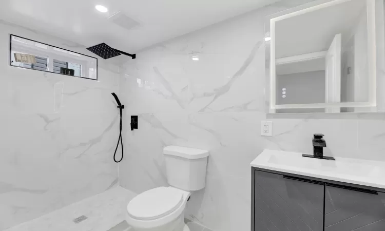 Full bathroom featuring a marble finish shower, recessed lighting, visible vents, toilet, and vanity