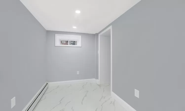 Basement featuring a baseboard heating unit, marble finish floor, recessed lighting, and baseboards