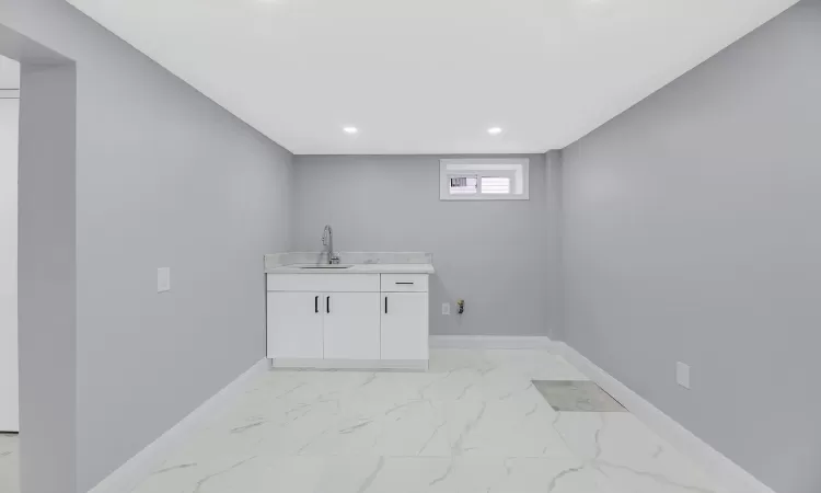 Clothes washing area featuring marble finish floor, baseboards, a sink, and recessed lighting