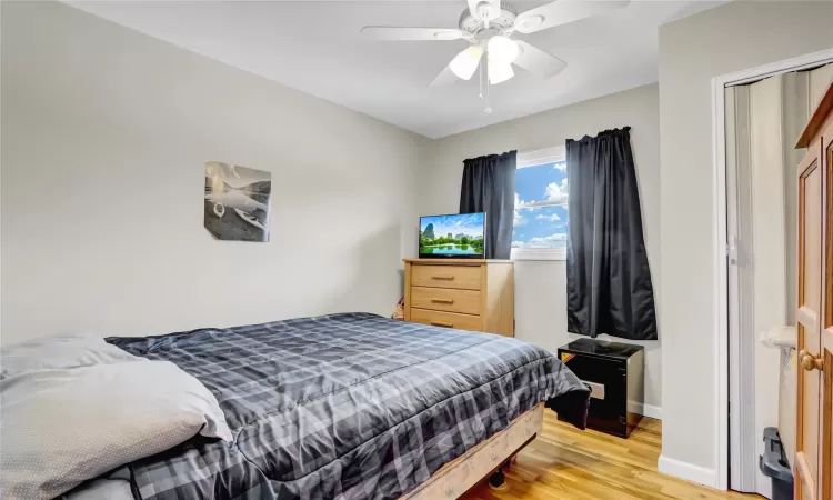 Bedroom with a ceiling fan, light wood-type flooring, and baseboards