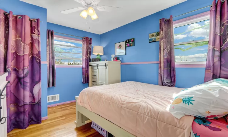 Bedroom featuring visible vents, ceiling fan, baseboards, and wood finished floors