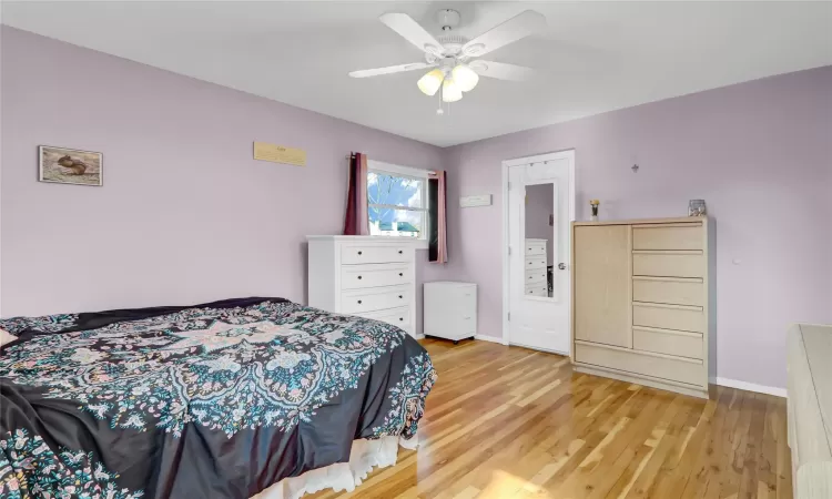 Bedroom featuring light wood finished floors, baseboards, and a ceiling fan