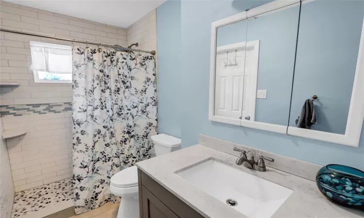 Bathroom featuring a stall shower, vanity, and toilet