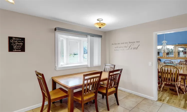 Dining room featuring light tile patterned floors, baseboards, a chandelier, and a wealth of natural light