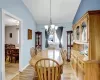 Dining space featuring vaulted ceiling, light wood finished floors, a chandelier, and baseboards