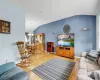 Living area featuring vaulted ceiling, a chandelier, light wood-style flooring, and baseboards