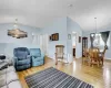 Living area featuring vaulted ceiling, baseboards, light wood-style flooring, and an inviting chandelier