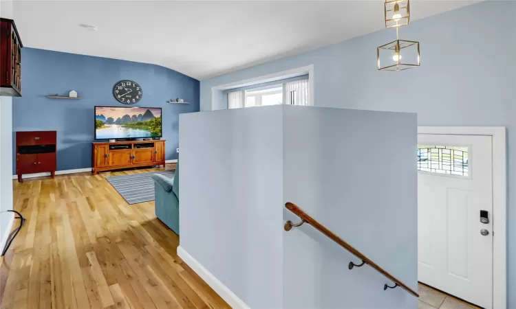 Hallway with light wood finished floors, baseboards, and an upstairs landing