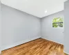 Empty room featuring a baseboard radiator, baseboards, and wood finished floors