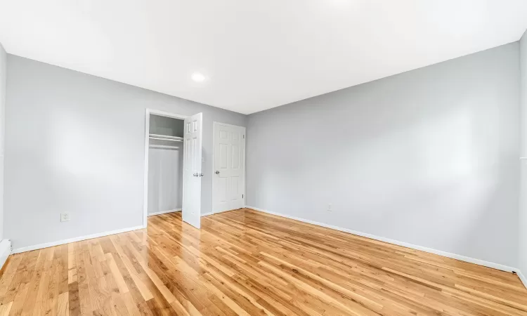 Unfurnished bedroom featuring light wood-style floors, a closet, and baseboards