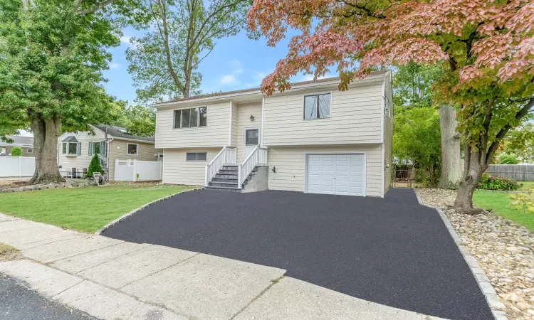 Split foyer home featuring a garage, a front yard, fence, and driveway