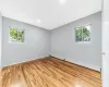 Spare room featuring a baseboard heating unit, plenty of natural light, wood finished floors, and baseboards