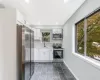 Kitchen featuring a sink, baseboards, white cabinets, light countertops, and appliances with stainless steel finishes