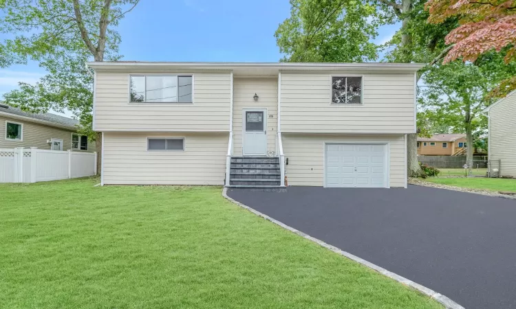 Raised ranch with an attached garage, a front yard, entry steps, fence, and driveway