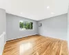 Unfurnished room featuring a baseboard radiator, baseboards, recessed lighting, and wood finished floors