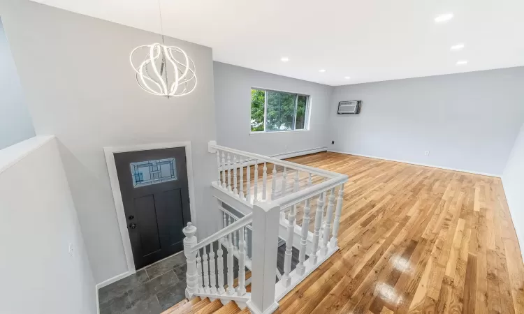 Foyer with recessed lighting, a notable chandelier, wood finished floors, baseboard heating, and a wall mounted AC