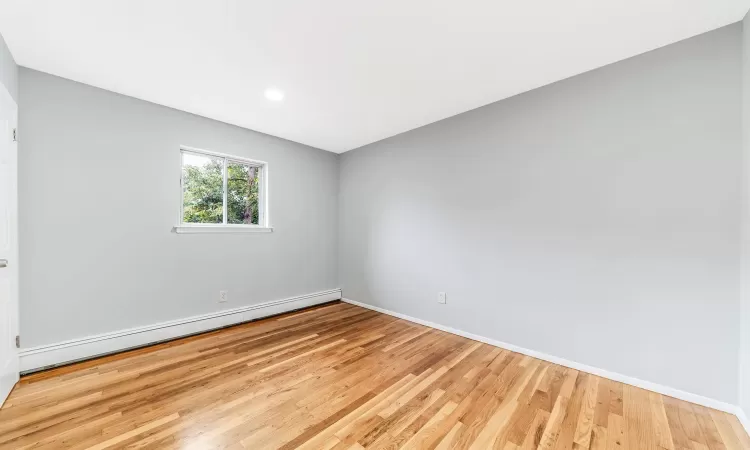 Unfurnished room with light wood-style floors, baseboards, and baseboard heating