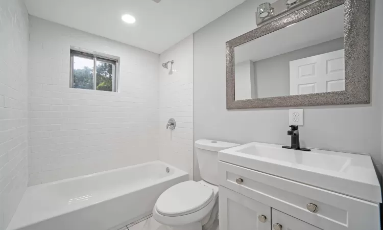 Bathroom featuring washtub / shower combination, vanity, toilet, and recessed lighting