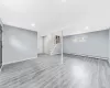 Basement with stairway, baseboards, a baseboard heating unit, and wood finished floors