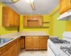 Kitchen featuring under cabinet range hood, a sink, light countertops, white range with gas stovetop, and ceiling fan