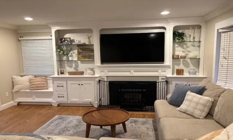 Living room with light wood-style floors, a fireplace, crown molding, and recessed lighting