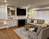 Living room featuring a fireplace with flush hearth, recessed lighting, dark wood-type flooring, and ornamental molding