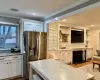 Kitchen with ornamental molding, a fireplace with flush hearth, stainless steel fridge with ice dispenser, and wood finished floors