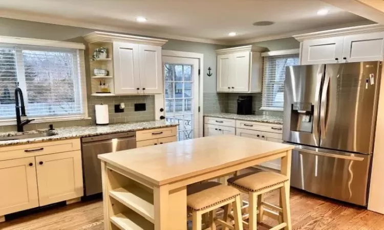 Kitchen with appliances with stainless steel finishes, a sink, ornamental molding, and open shelves