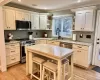 Kitchen featuring light wood-style flooring, appliances with stainless steel finishes, crown molding, open shelves, and a sink